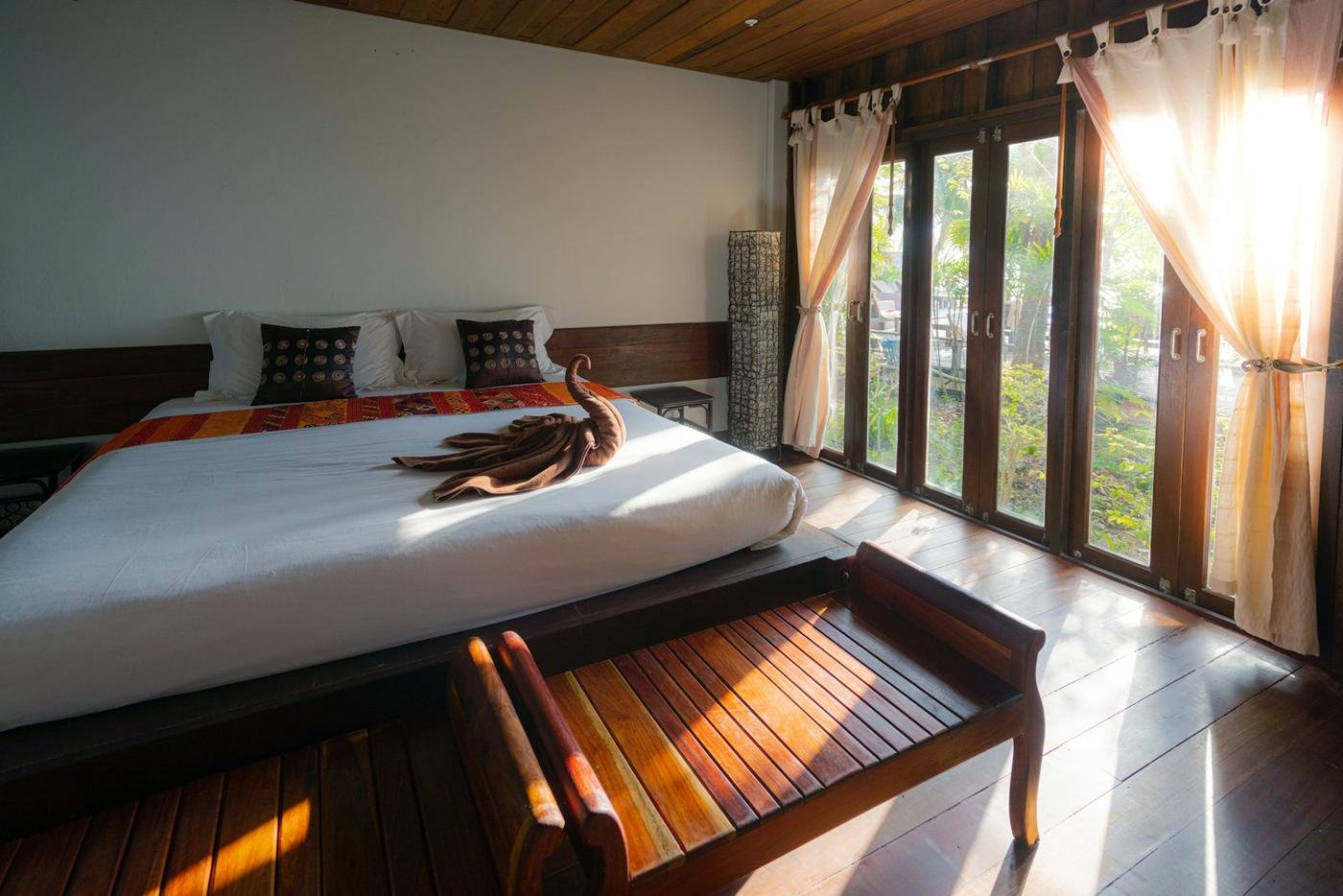Wooden-floored room with a bed and doors open to the garden